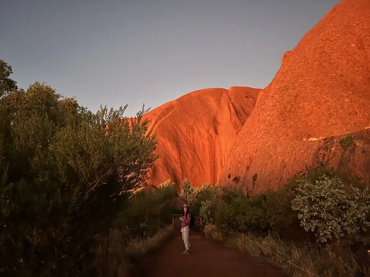 Walking the base trail at Uluru with the massive rock towering above