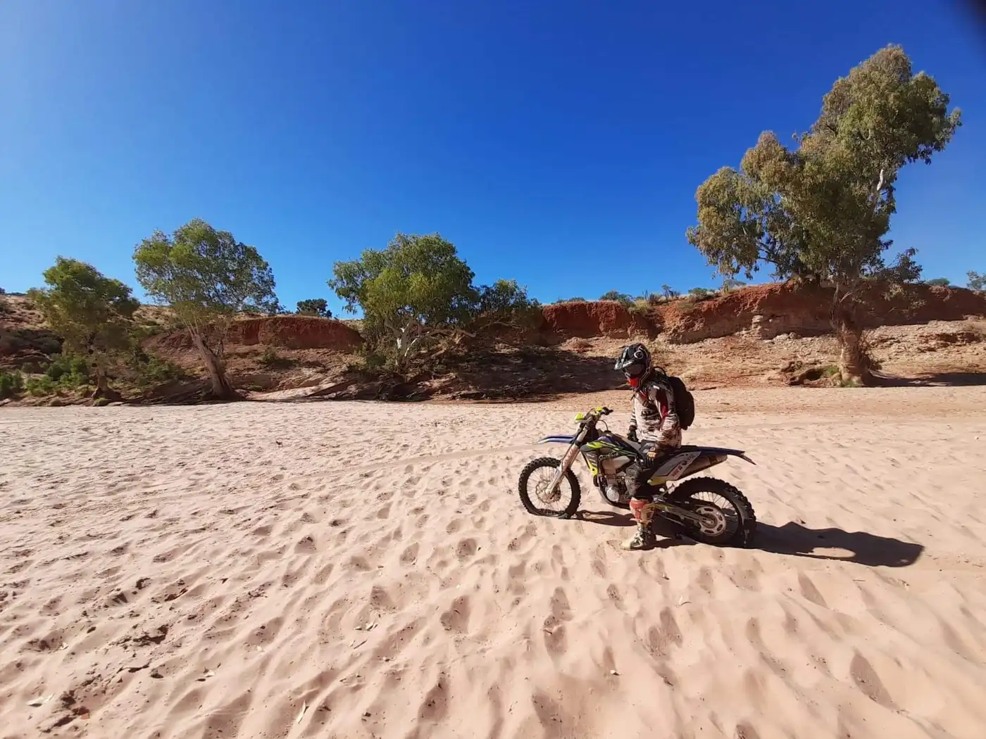 Motorcycle rider navigating a sandy river crossing on the Finke Track